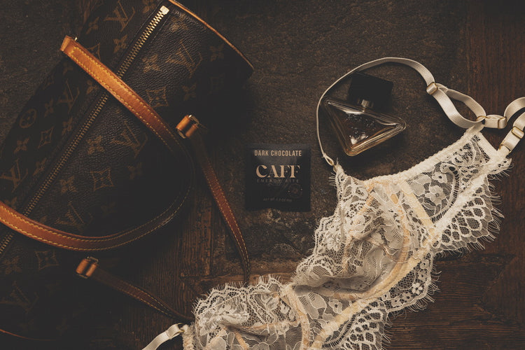 A Dark Chocolate CAFF bite with a leather handbag, perfume and lace